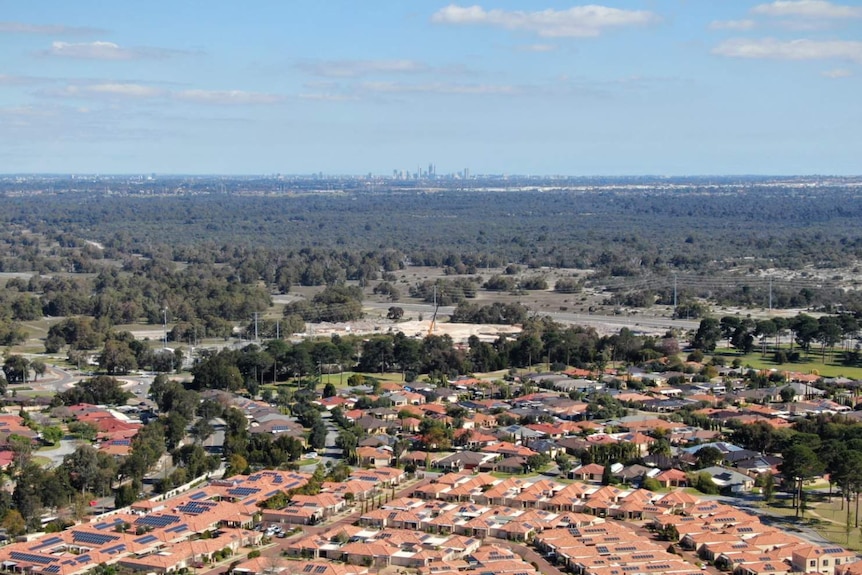 An aerial shot of a residential neighbourhood, looking back towards a city skyline