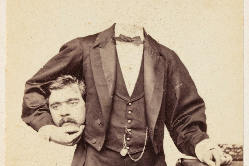 A man appearing to hold his own head under his arm.