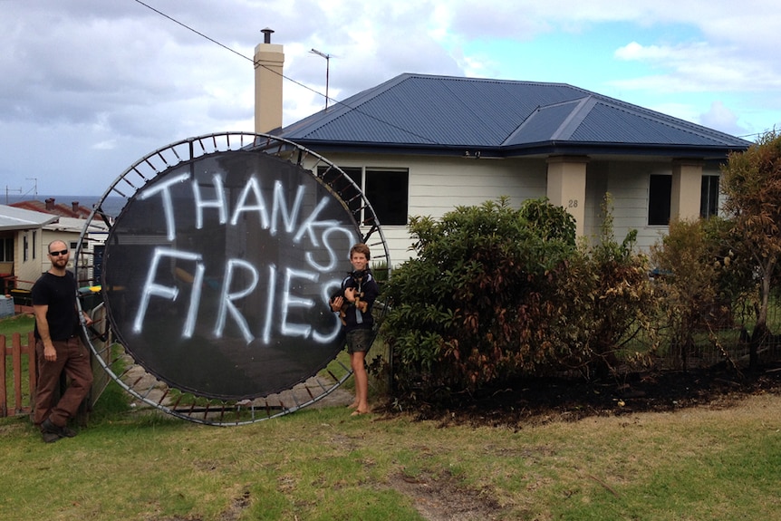 Man and boy standing next to Thank You Firies sign painted on trampoline