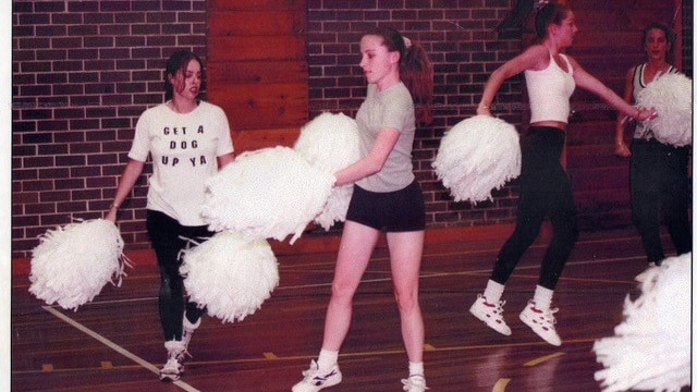 Young women in casual clothes practising cheerleading with pom poms.