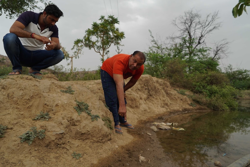 Sandeep Katana (L) and community leader Ram Niwas, pointing out Leopard paw prints at a dam outside Mandawar village.