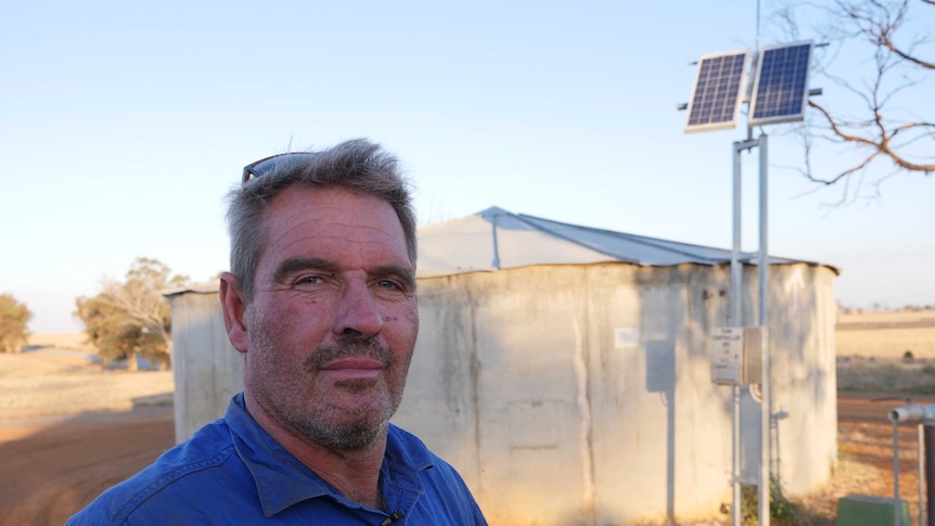 Pig farmer Tony Richardson stands beside a standpipe in regional WA.