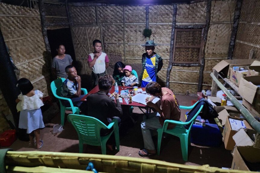 people sitting at table inside a thatched hut.