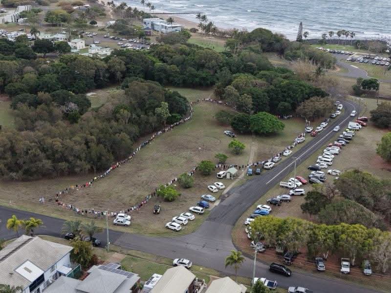 An aerial photo of a park with hundreds of people holding hands