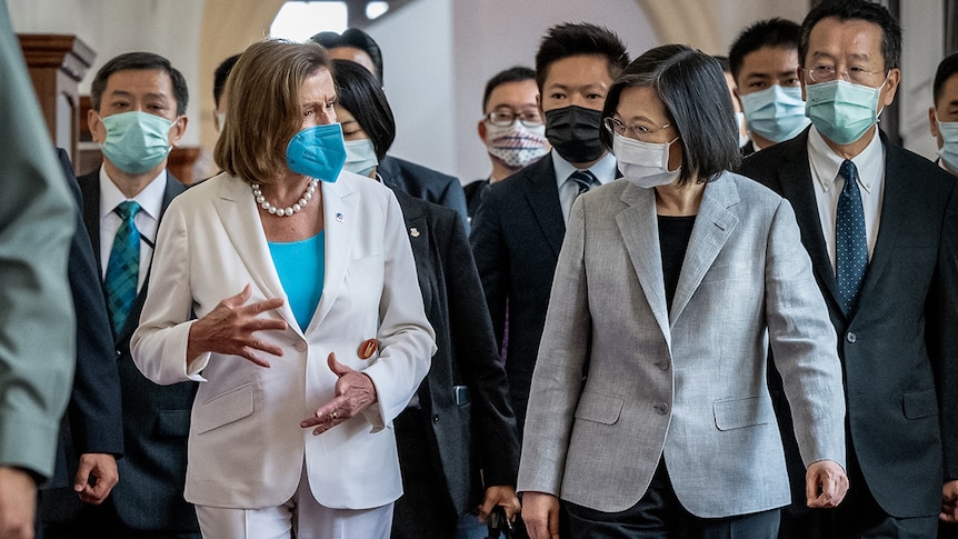Nancy Pelosi and Tsai Ing-wen walking and talking with hand gestures, many people in suits walk behind them