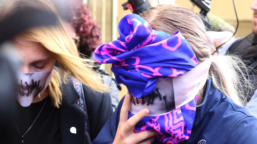 A 19-year old British woman, right, covers her face as she leaves court.