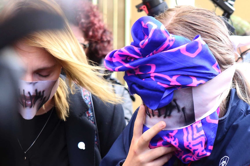 A 19-year old British woman, right, covers her face as she leaves court.