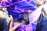 A 19-year old British woman, right, covers her face as she leaves court.