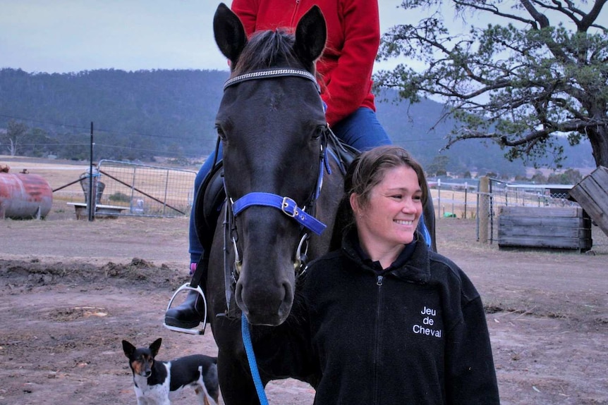 Lizzie Donovan standing next to a horse with a rider.