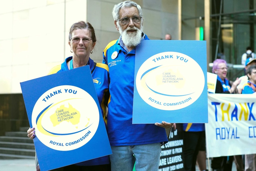 A woman and a man holding national redress placards.