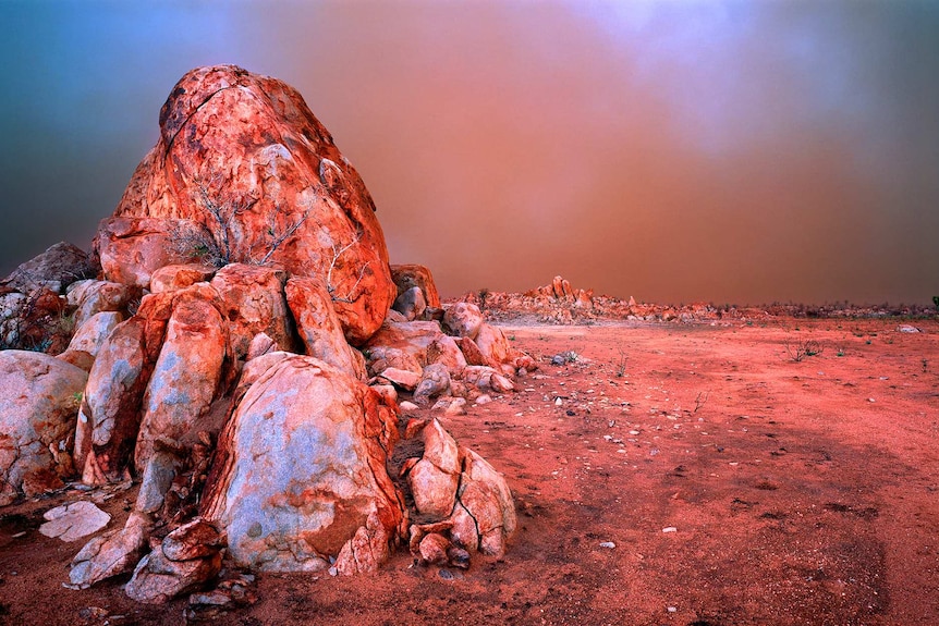 A red landscape fringed with rock formations.