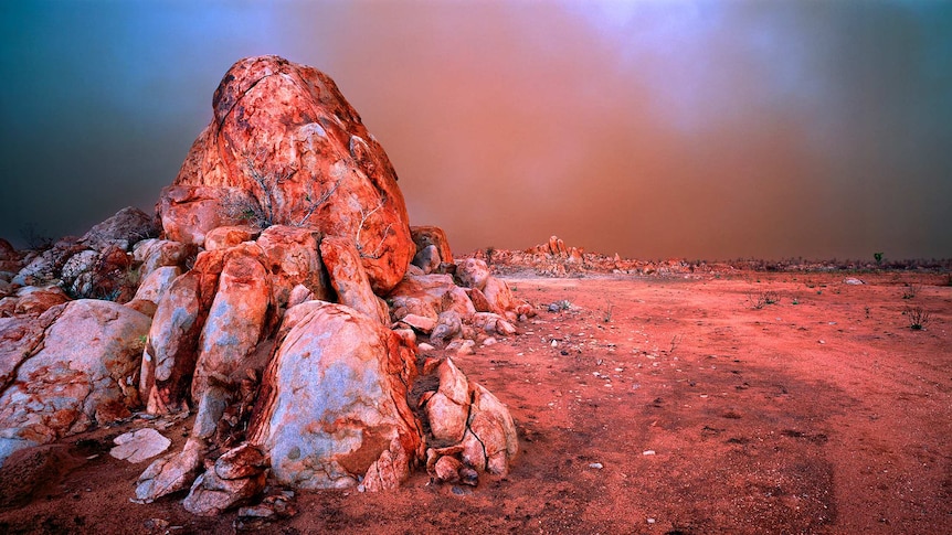 A red landscape fringed with rock formations.
