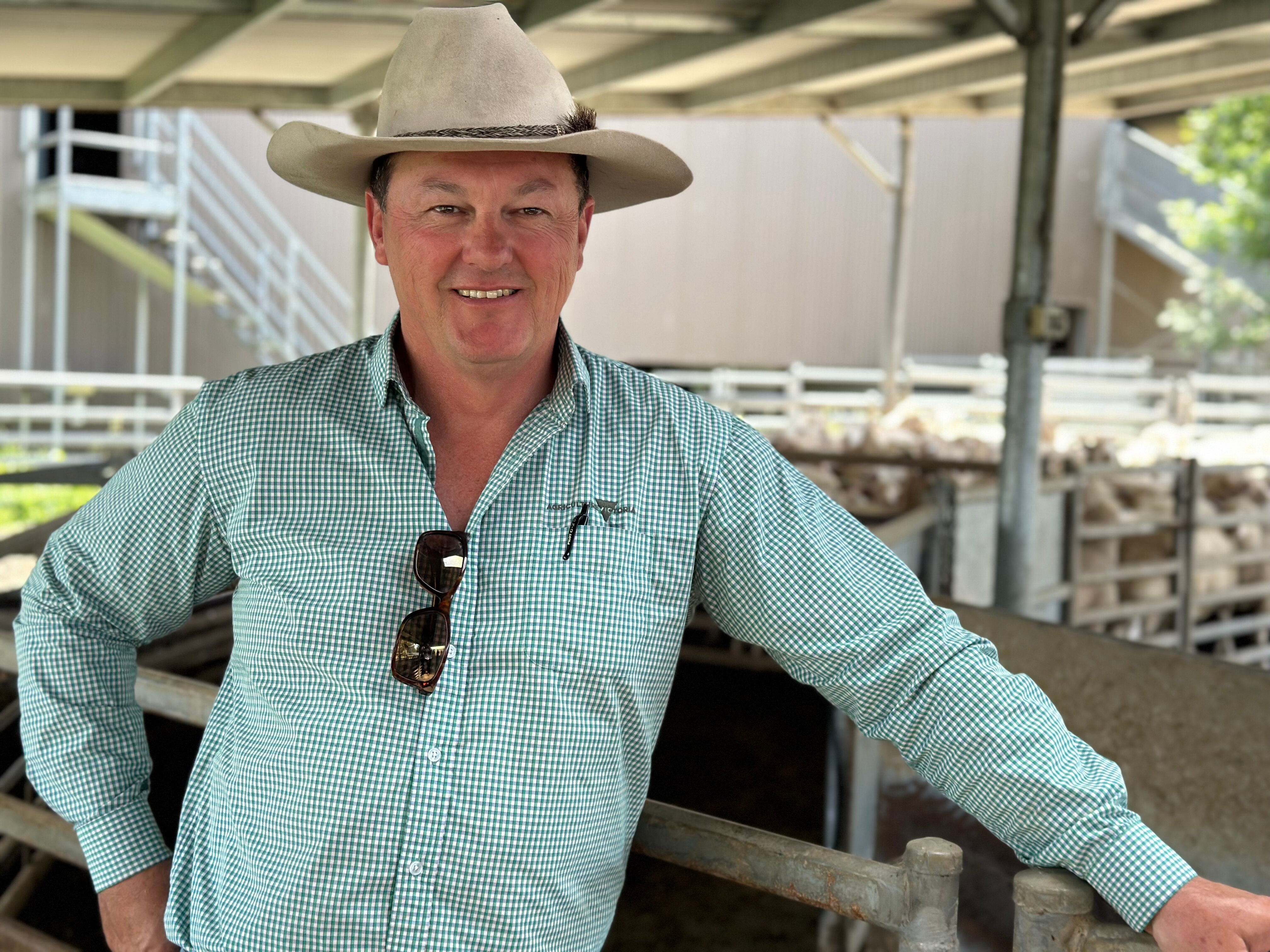 a man wearing a hat standing in sheep yards