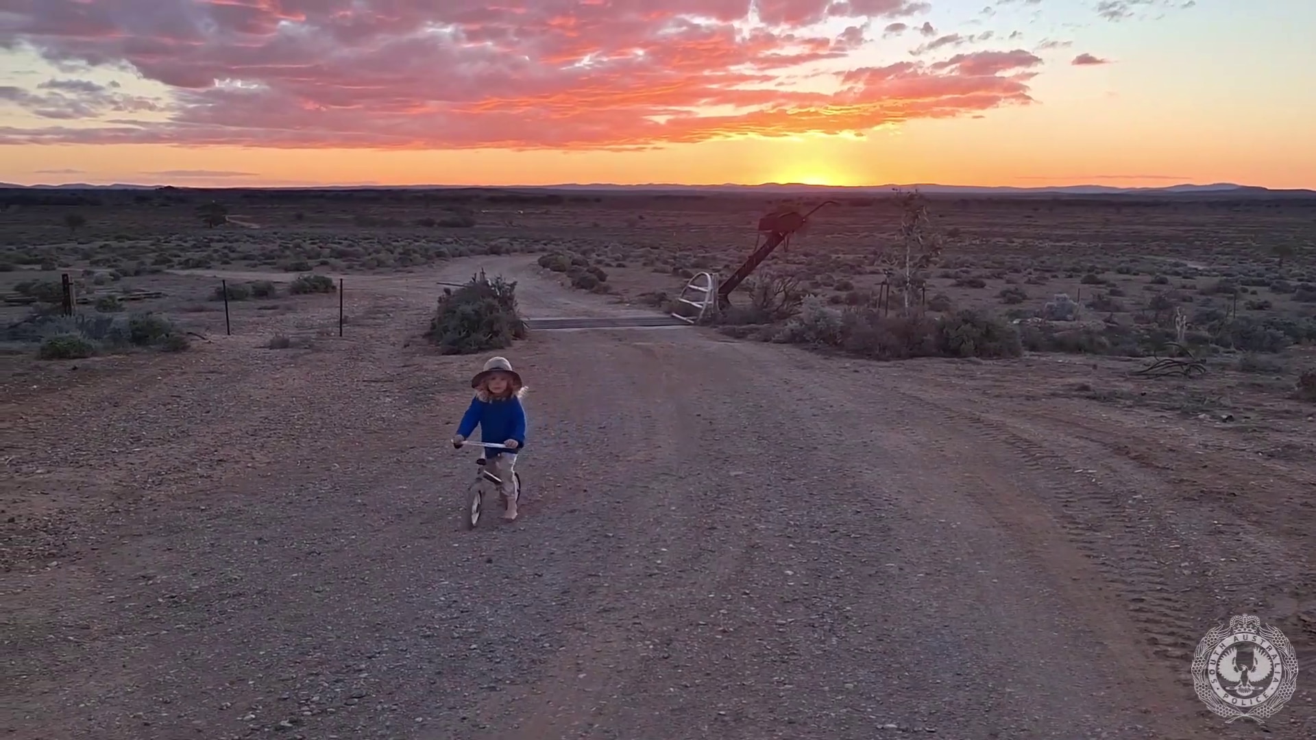 Little boy riding a toy bike against a majestic sunset in an arid landscape.