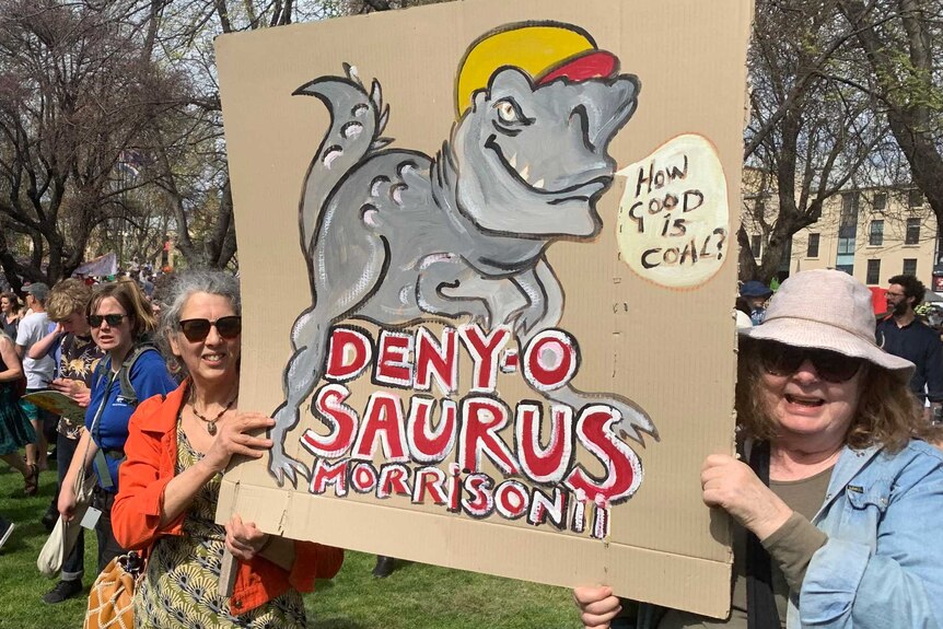 Protesters hold a sign depicting Prime Minister Scott Morrison as a dinosaur at a Hobart climate change rally