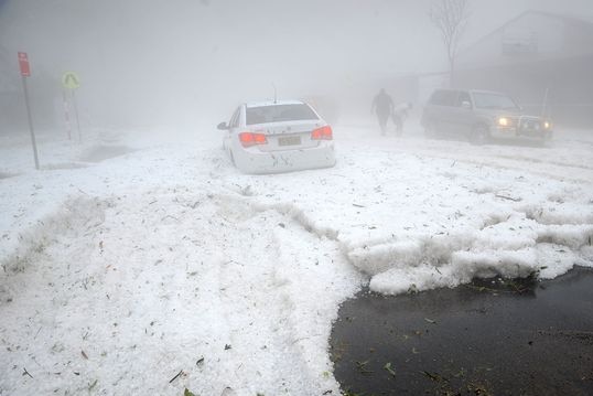 Hail blankets a road and a car.