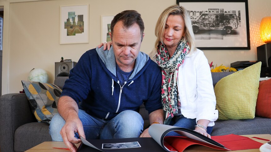 Couple sitting on the couch, flicking through a photo album.