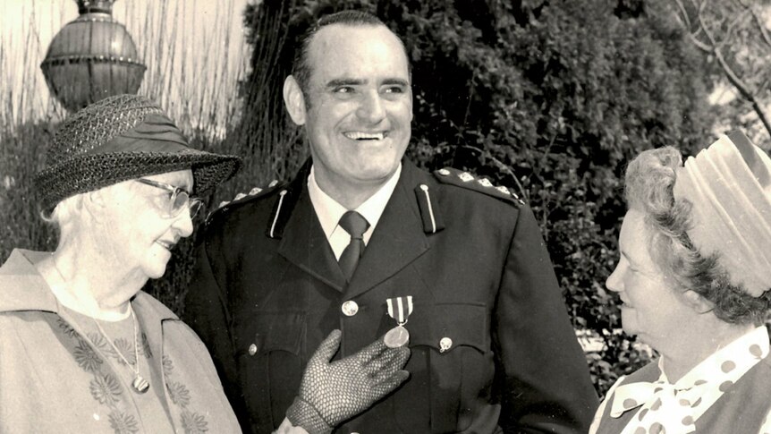 John 'Jack' Thomas wearing a medal and flanked by two women.