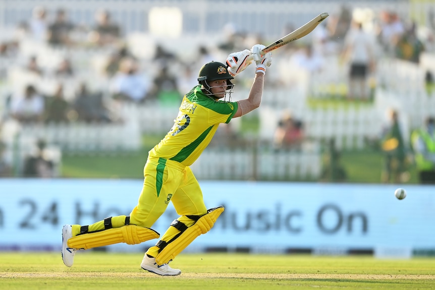 An Australian batsman watches the ball fly away after playing a shot on the off-side in a T20 World Cup game.