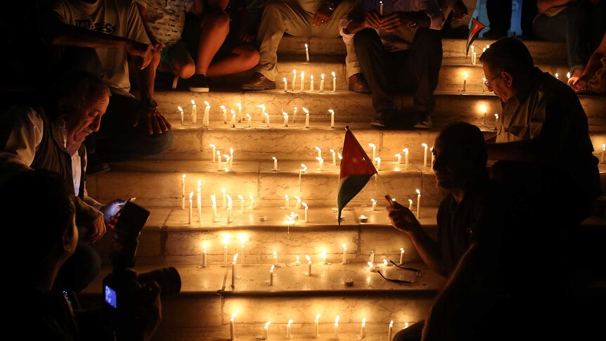 Jordanians in Amman hold candles at a vigil for six Jordanian soldiers killed in a suicide bombing on their border with Syria