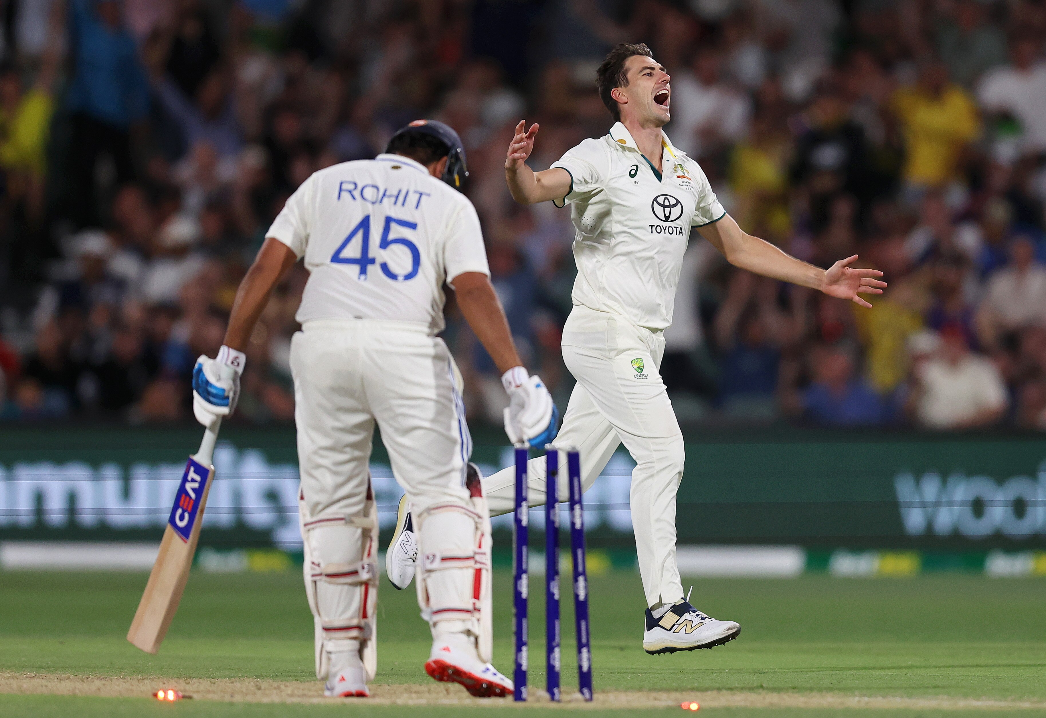 Australia bowler Pat Cummins celebrates the wicket of India batter Rohit Sharma, in the foreground.