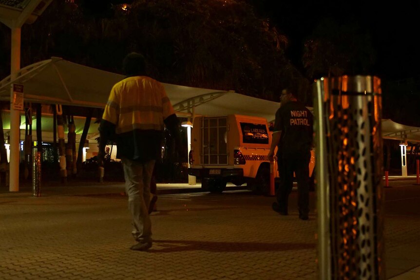 A man is escorted towards a night patrol van by police.