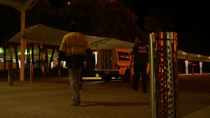 A man is escorted towards a night patrol van by police.