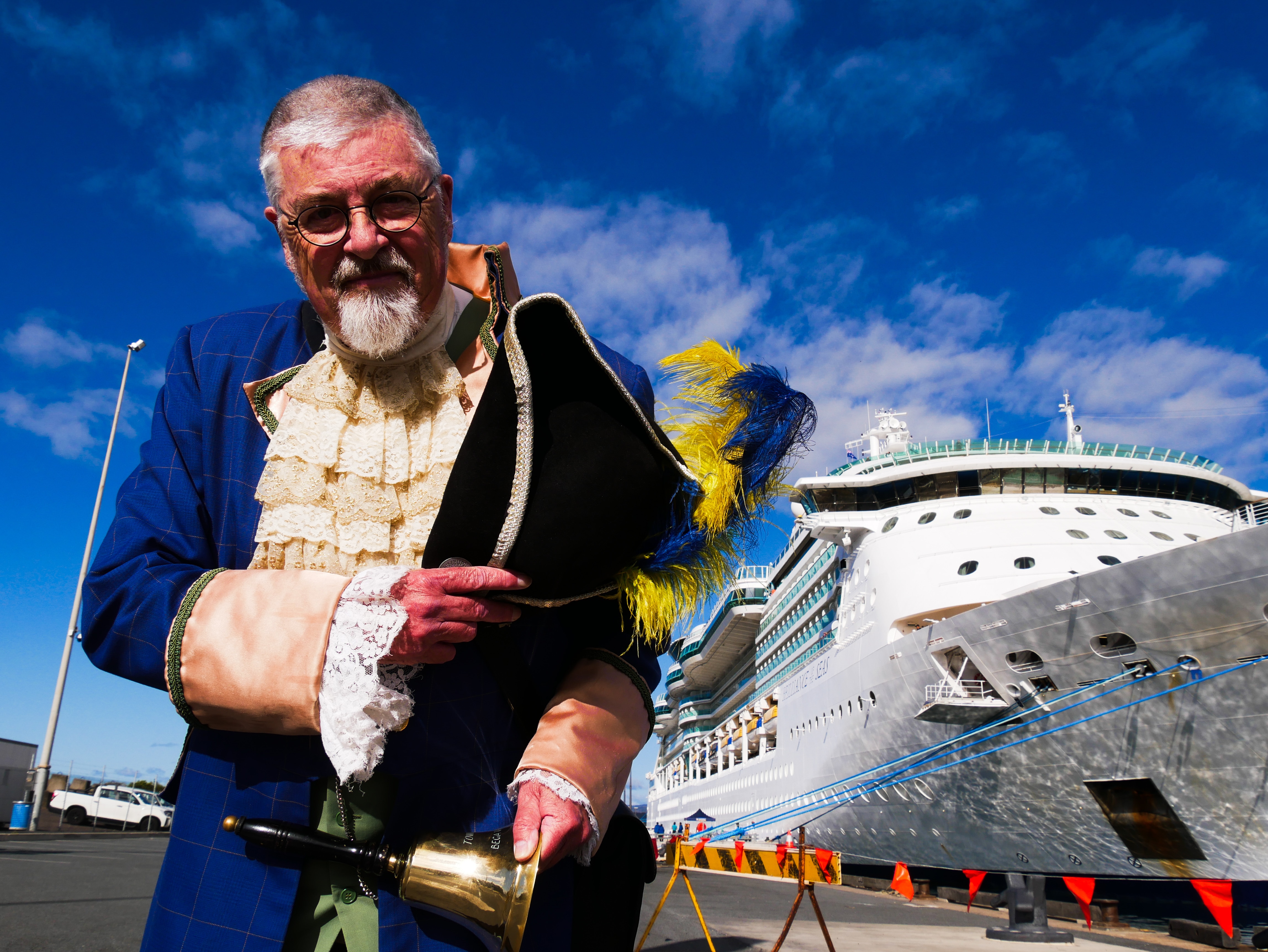 a man bows with a pirate hat in front of a huge ship