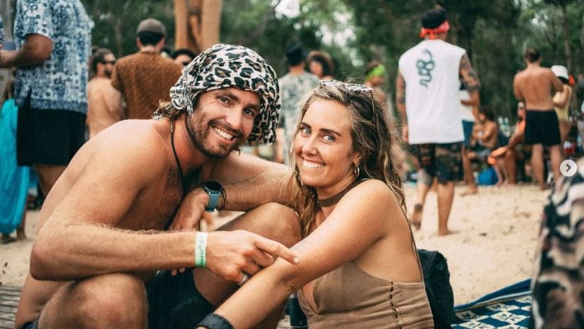 A man and a woman posing for a photo at a festival, smiling