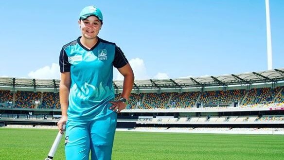 Ash Barty on a cricket pitch holding a bat.