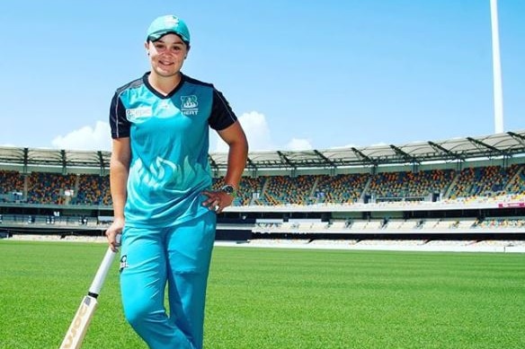 Ash Barty on a cricket pitch holding a bat.