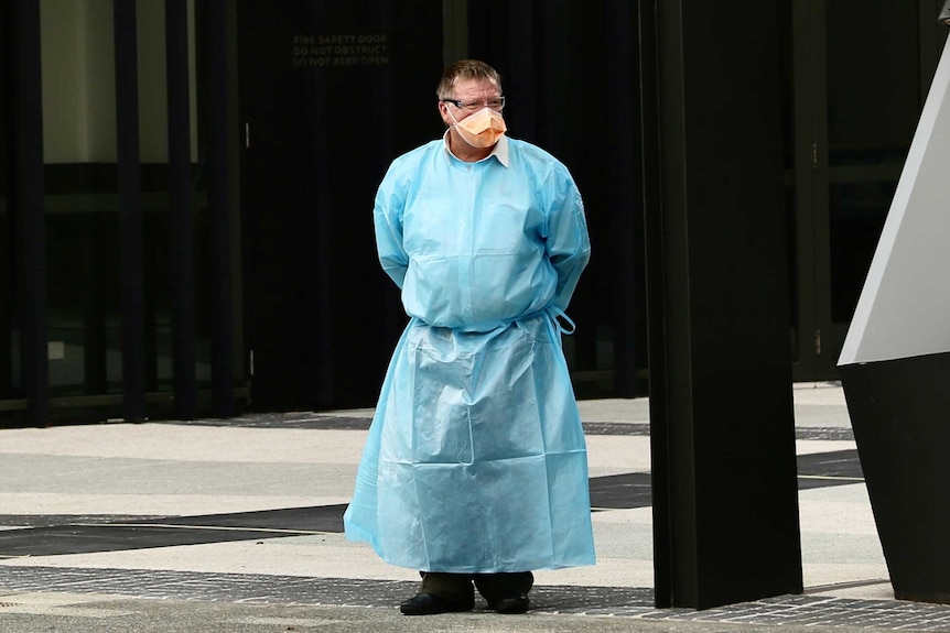 A Transperth bus driver wears PPE outside a Perth hotel, including an orange mask and safety glasses.