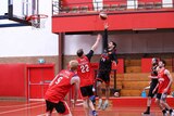 basketball player attempts slamdunk while opponent  attempts to block and other players stand by