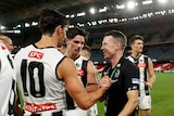 Craig McRae and Scott Pendlebury smile and shake hands after an AFL match.