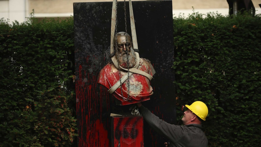 A bust of Belgium's King Leopold II, is hoisted off of its plinth by a crane as it's removed from a park in Ghent, Belgium.