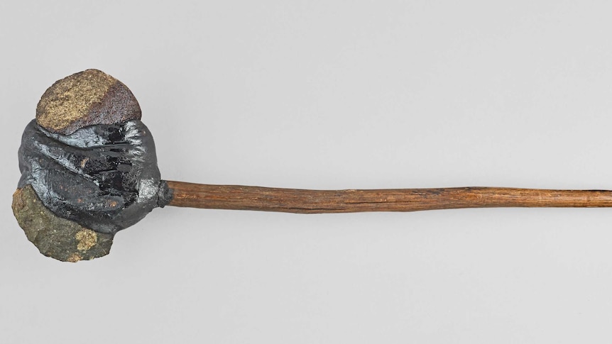 A rock attached to a slim wooden handle.