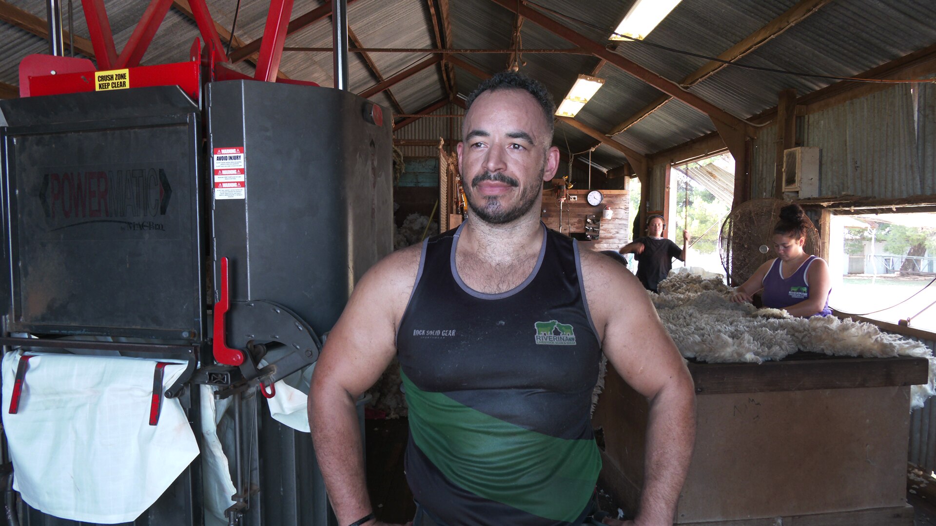 A man standing in a shearing shed. 