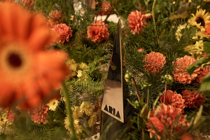 An ARIA award surrounded by orange flowers and greenery