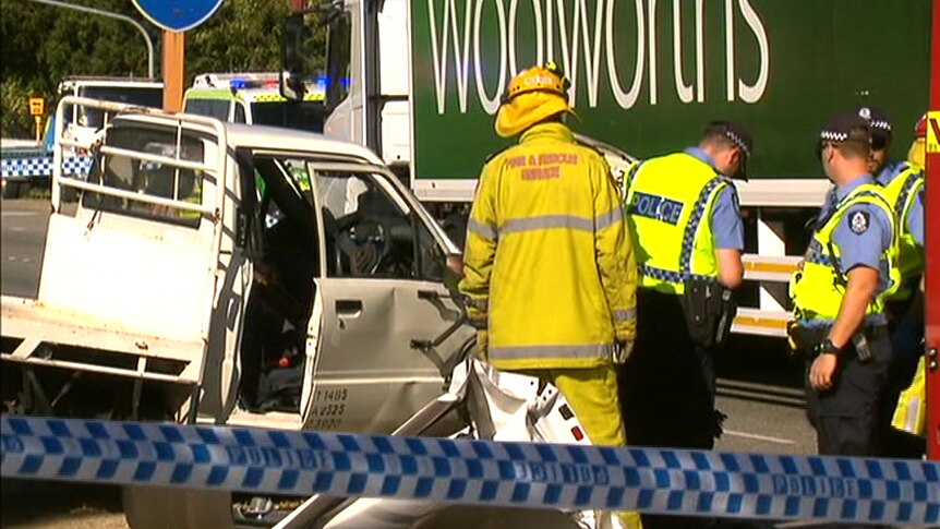 Emergency crews around a smashed white ute in front of a Woolworths truck.