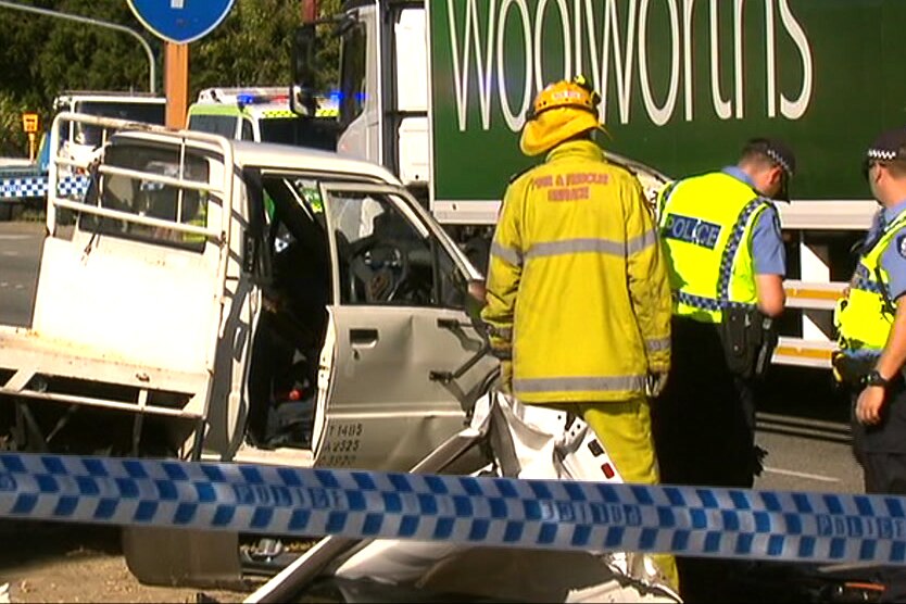 Emergency crews around a smashed white ute in front of a Woolworths truck.