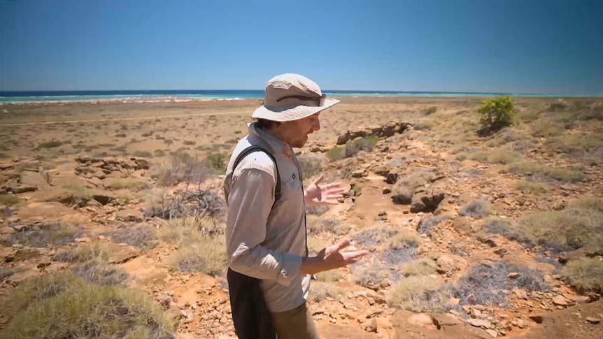 A man walks along land at Cape Range by the sea