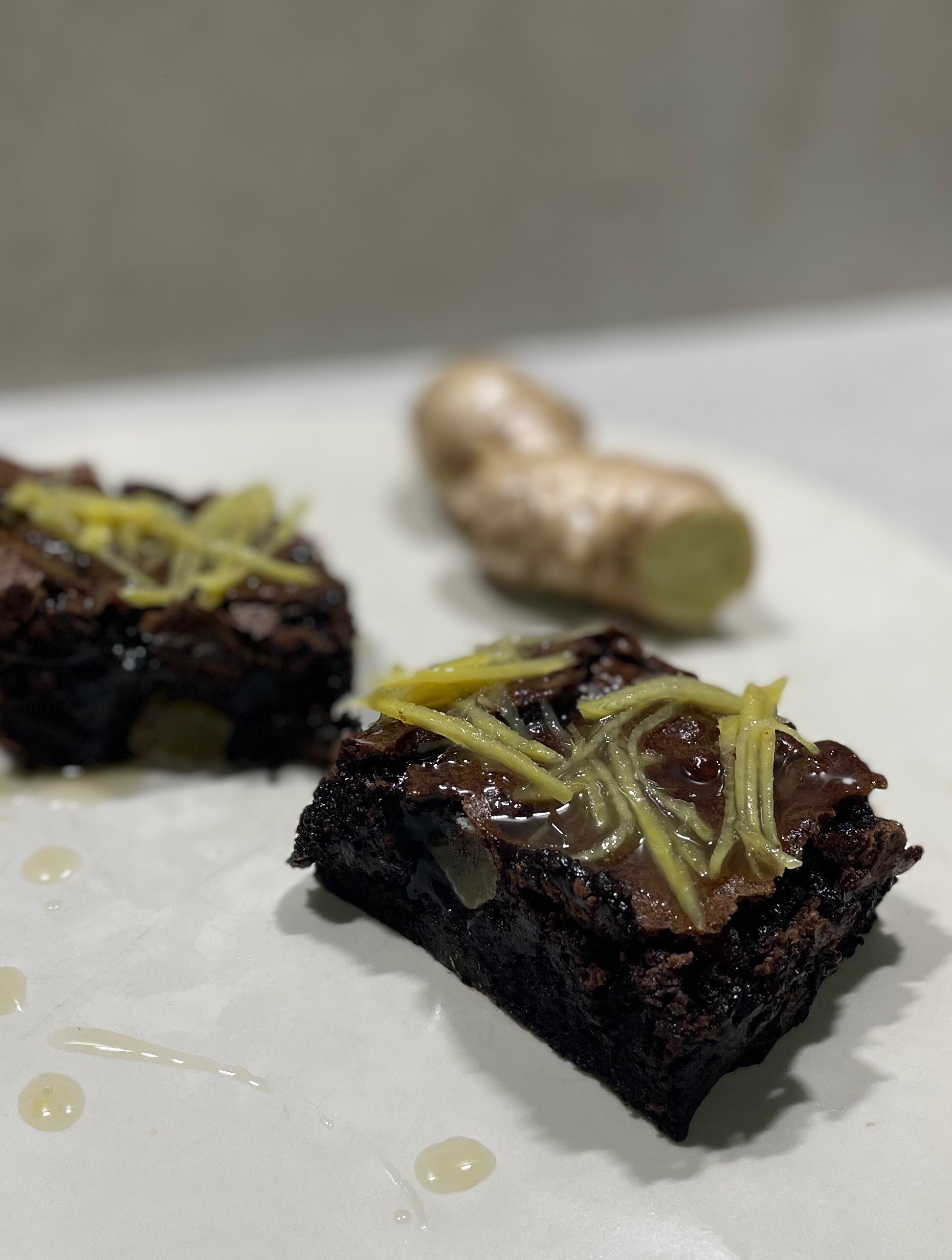 Close-up of two chocolate and ginger brownie pieces, with ginger strips on top.