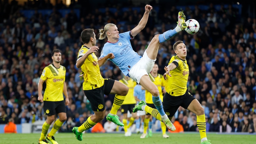 Erling Haaland of Manchester City jumps to kick a soccer ball against Borussia Dortmund.