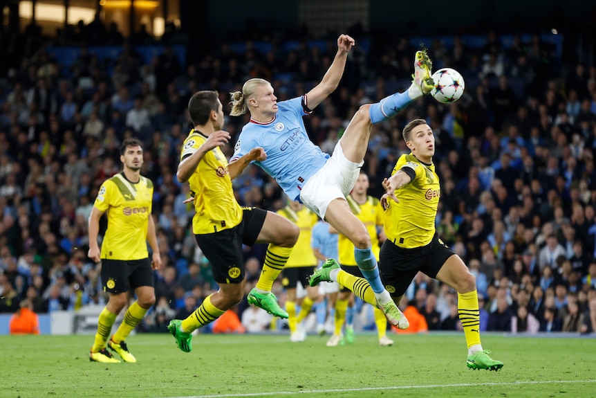 Erling Haaland of Manchester City jumps to kick a soccer ball against Borussia Dortmund.