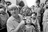 Dr Hollows points to a young boy's eye while a crowd of onlookers stare