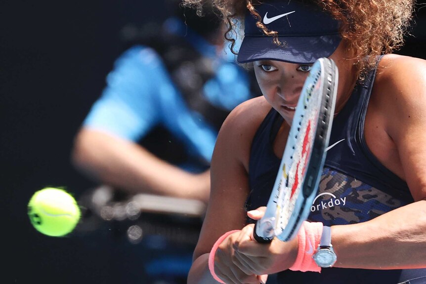 Naomi Osaka stares at the ball intently as she prepares to play a backhand stroke
