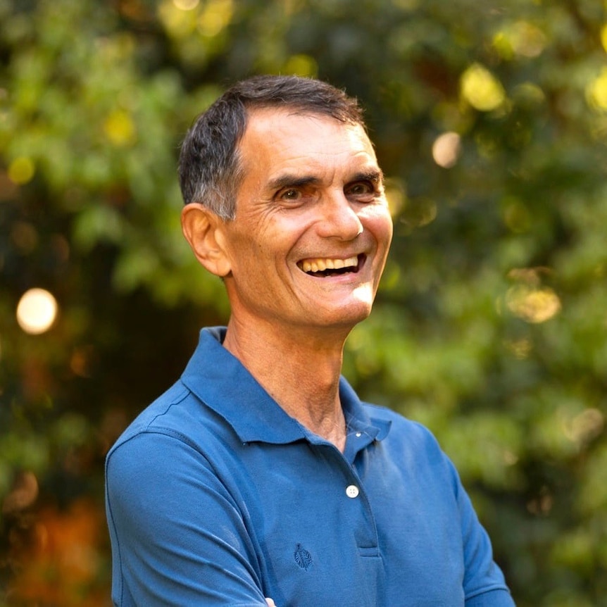A man wearing a blue shirt smiles 