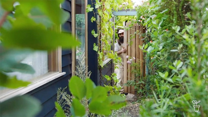 Man entering a side garden through a wooden gate.