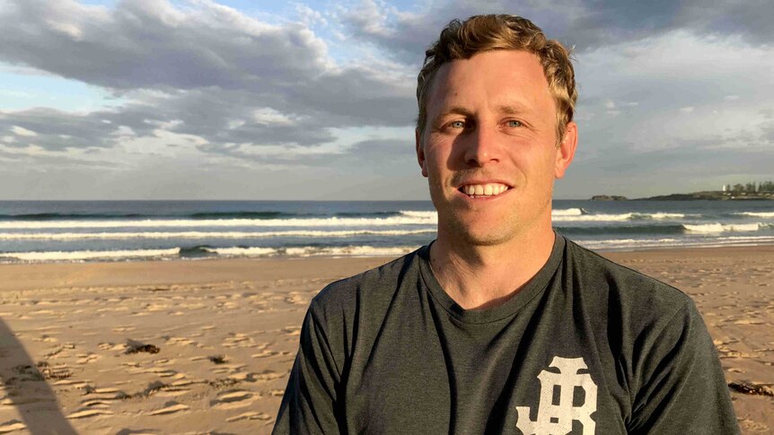 A young man standing on the beach.