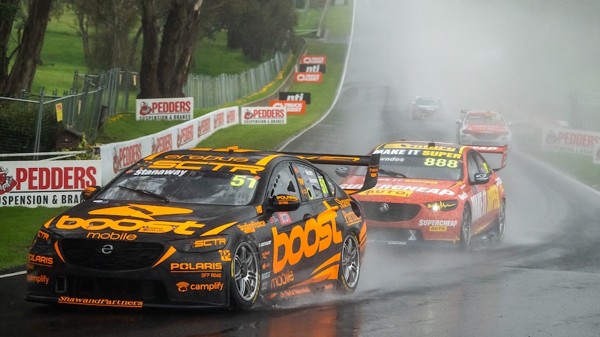 Richie Stanaway drives a Holden in the wet with spray coming up behind him